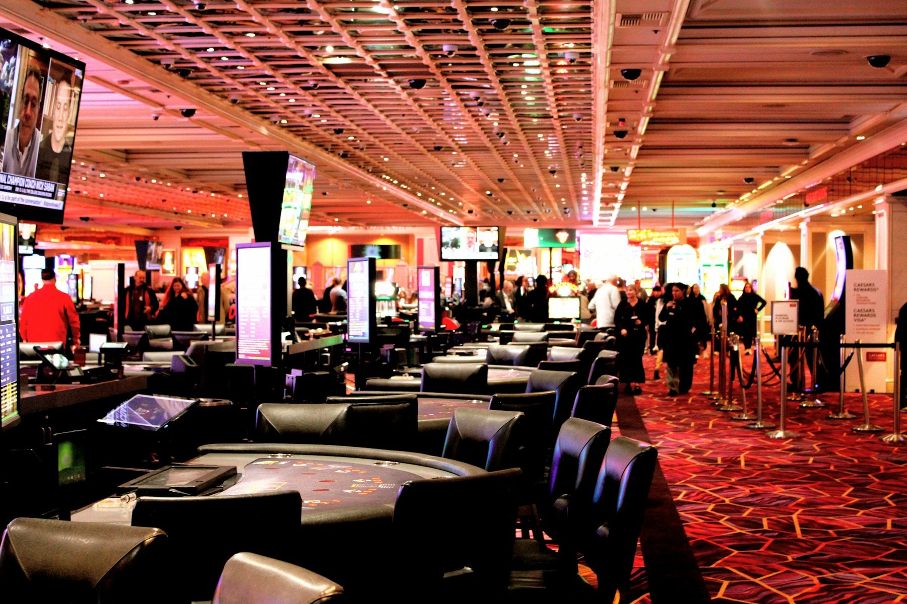 Guests moving through a casino floor lined with gaming tables under warm light.