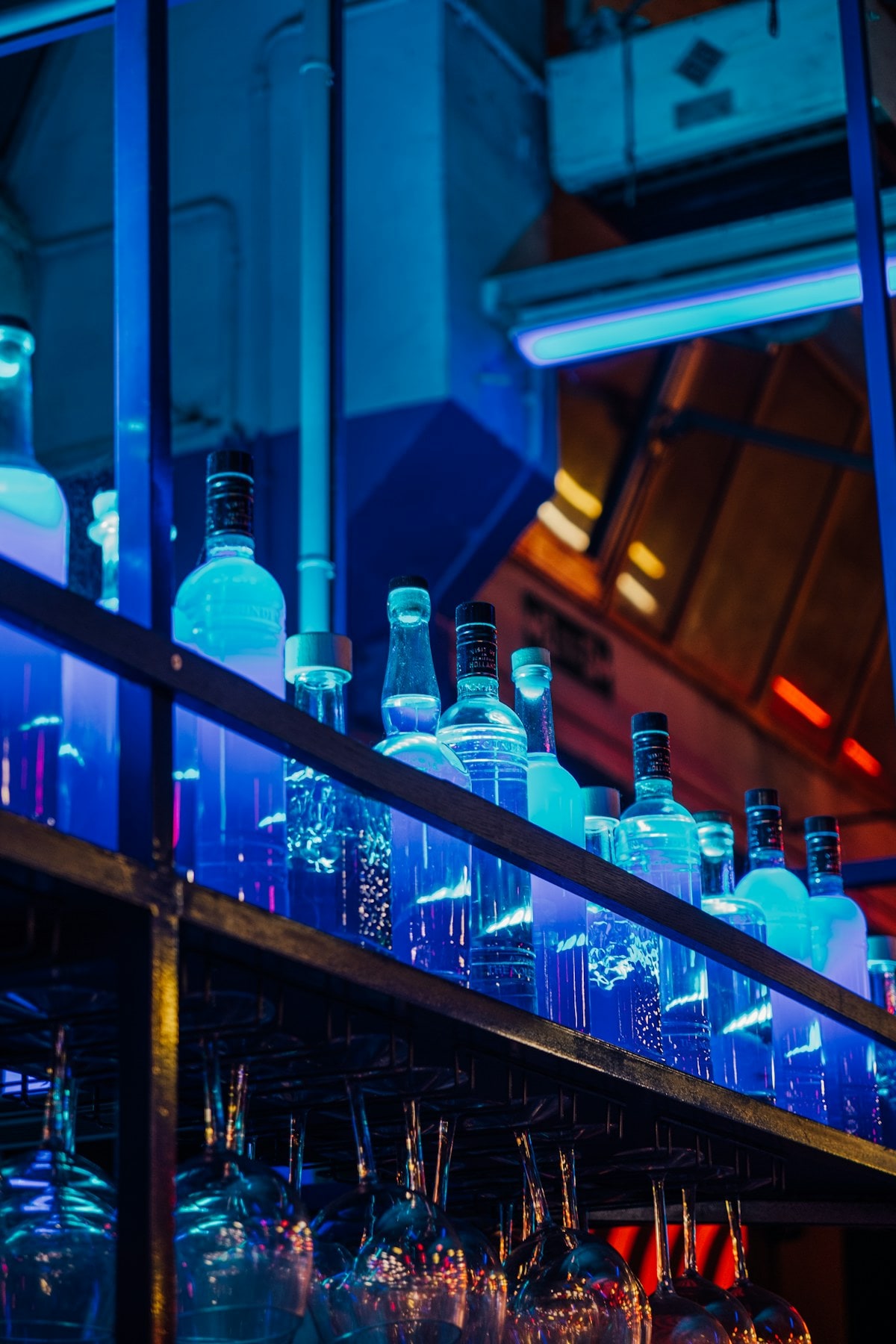 Bottles lit from behind in cool blue light along a bar shelf.