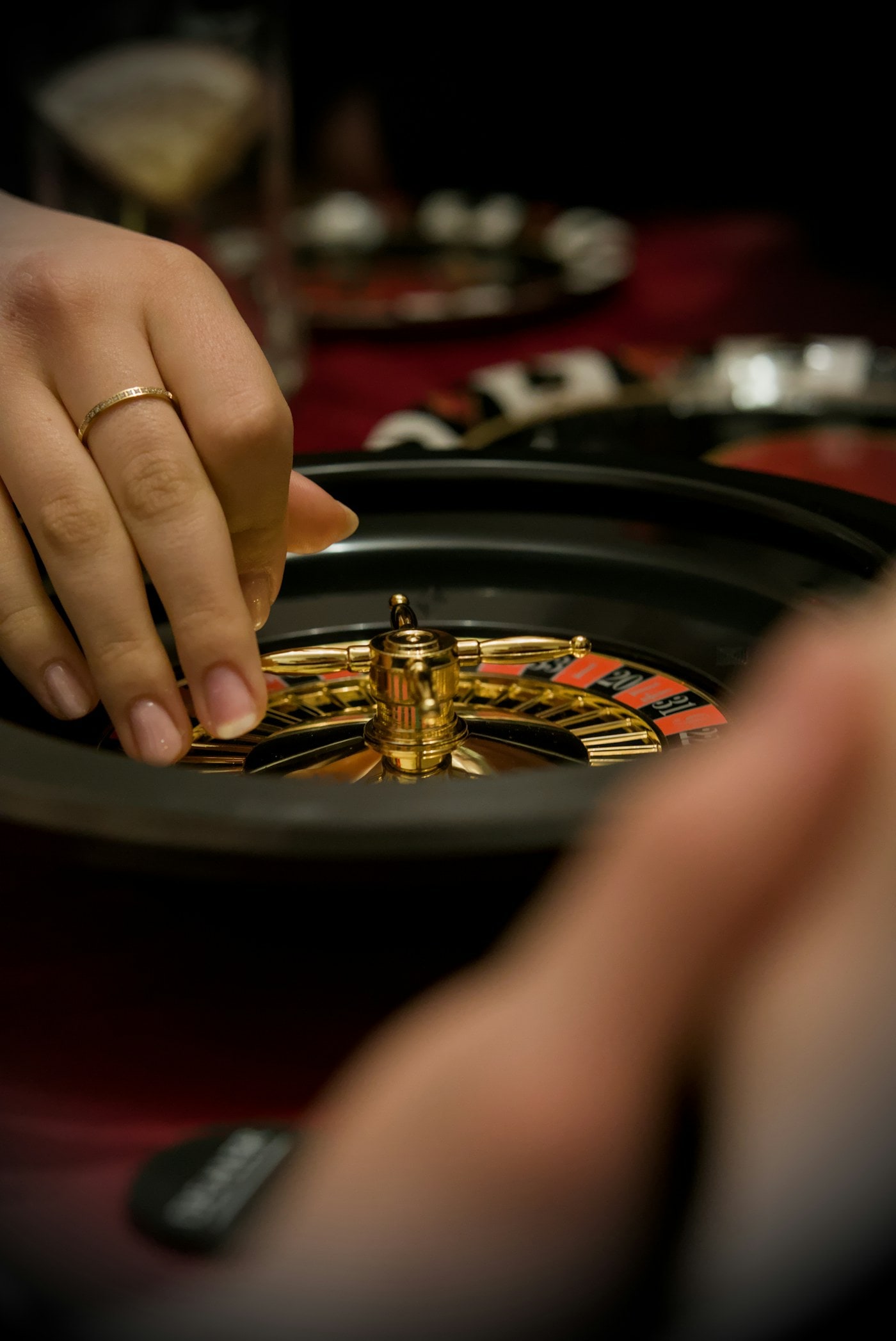 A hand resting on the rim of a polished roulette wheel.
