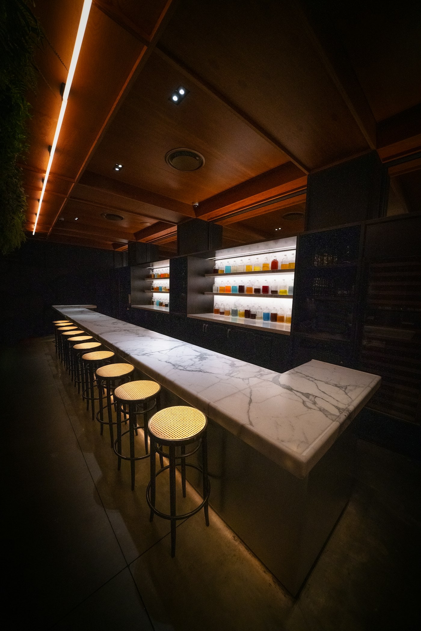 A marble bar counter with stools in a softly lit interior.