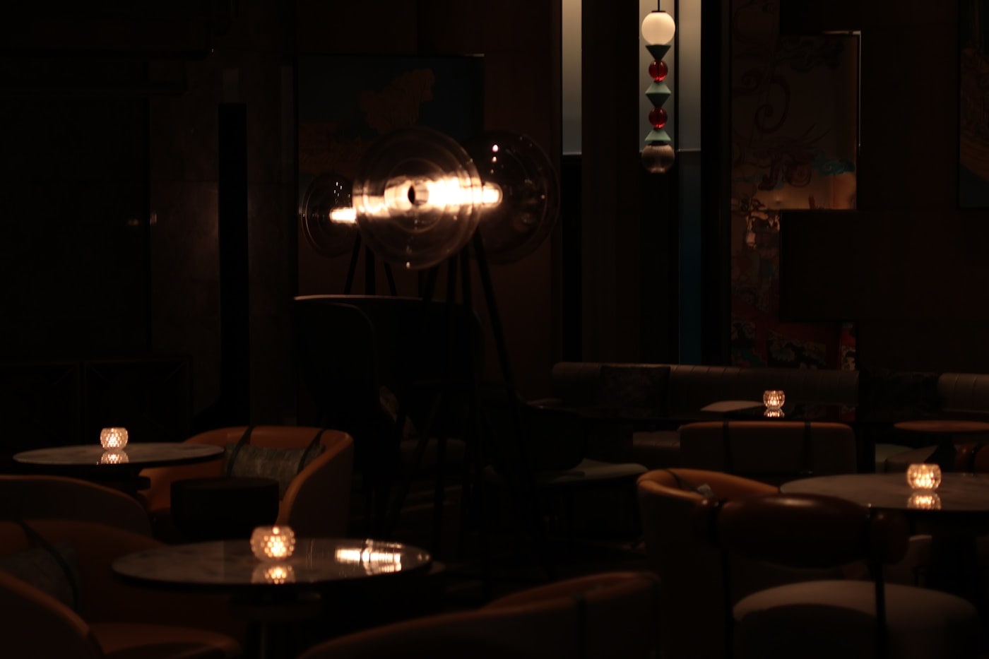 A dark lounge with candlelit tables and a single warm lamp.